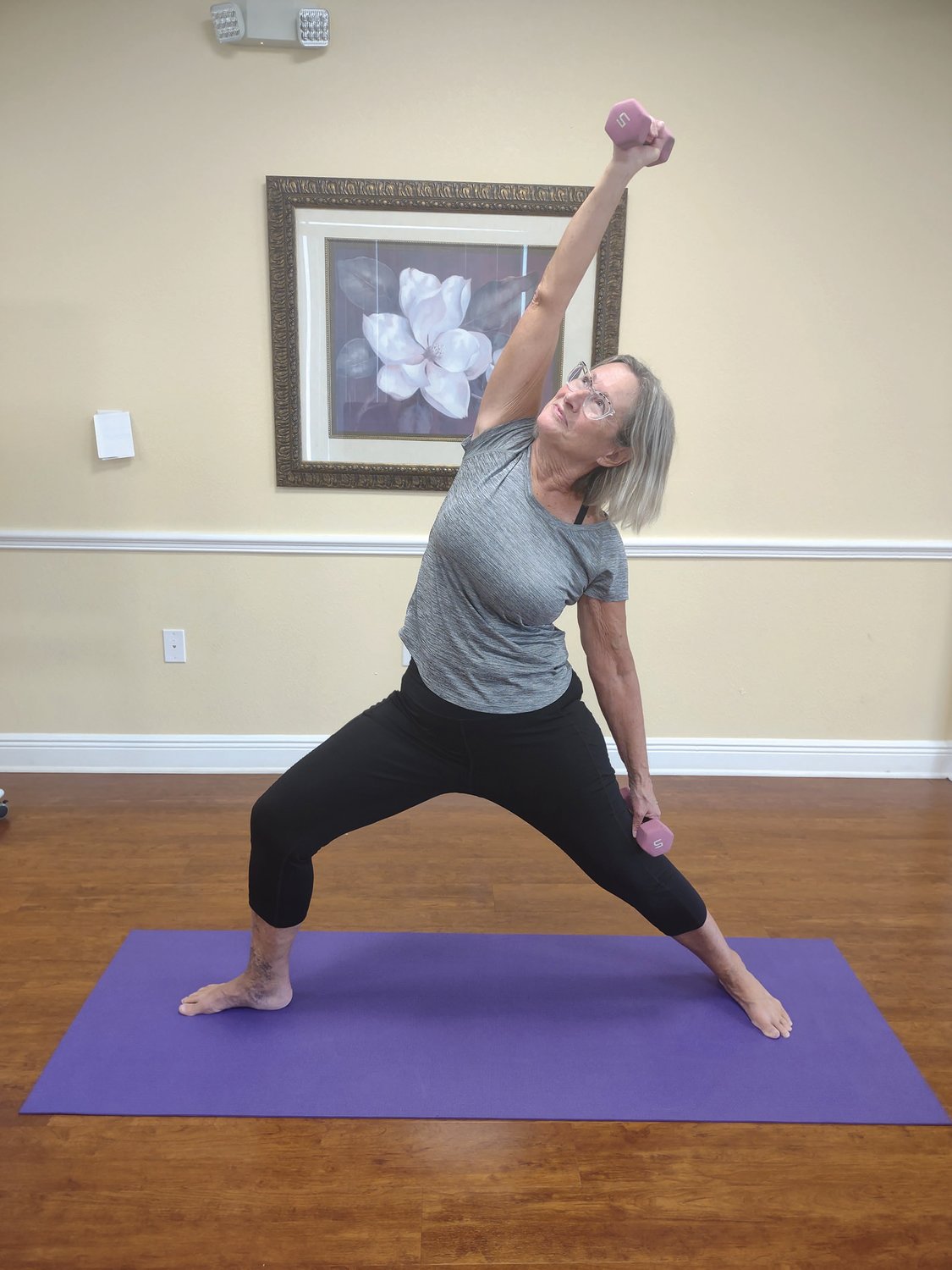 Observe in the photo, Mary Loe, Yoga practioner -- at the Shield Medical Group in Sebring -- performing “Modified Warrior Pose” using 2-pound weights in each hand. One arm is extended straight down the thigh with a deep knee bend and the other arm lengthened down the opposite leg. Hold this posture for several long breaths to strengthen core muscles. You can do it!